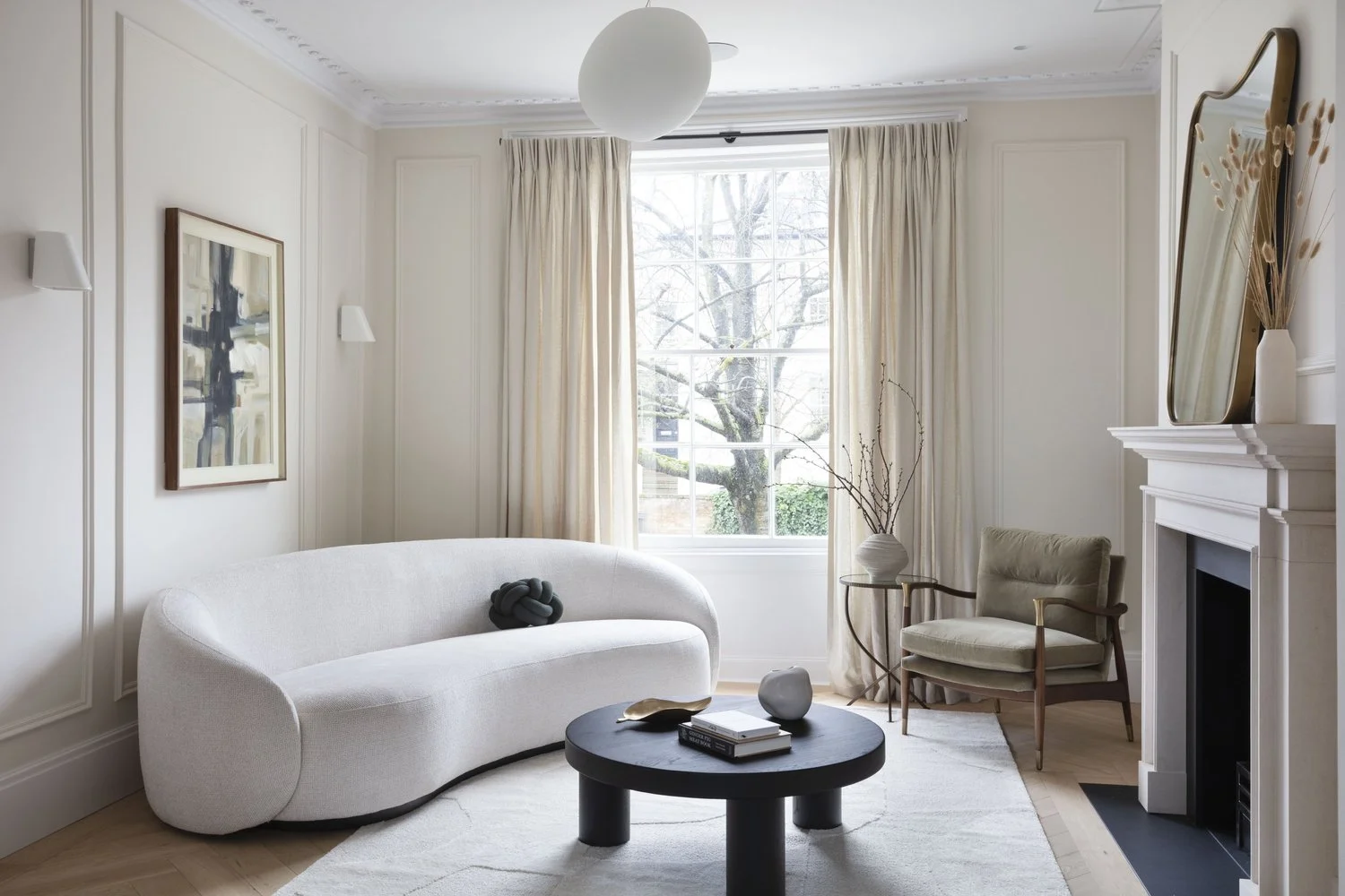 Sculptural white sofa, traditional fireplace and a generous sash window