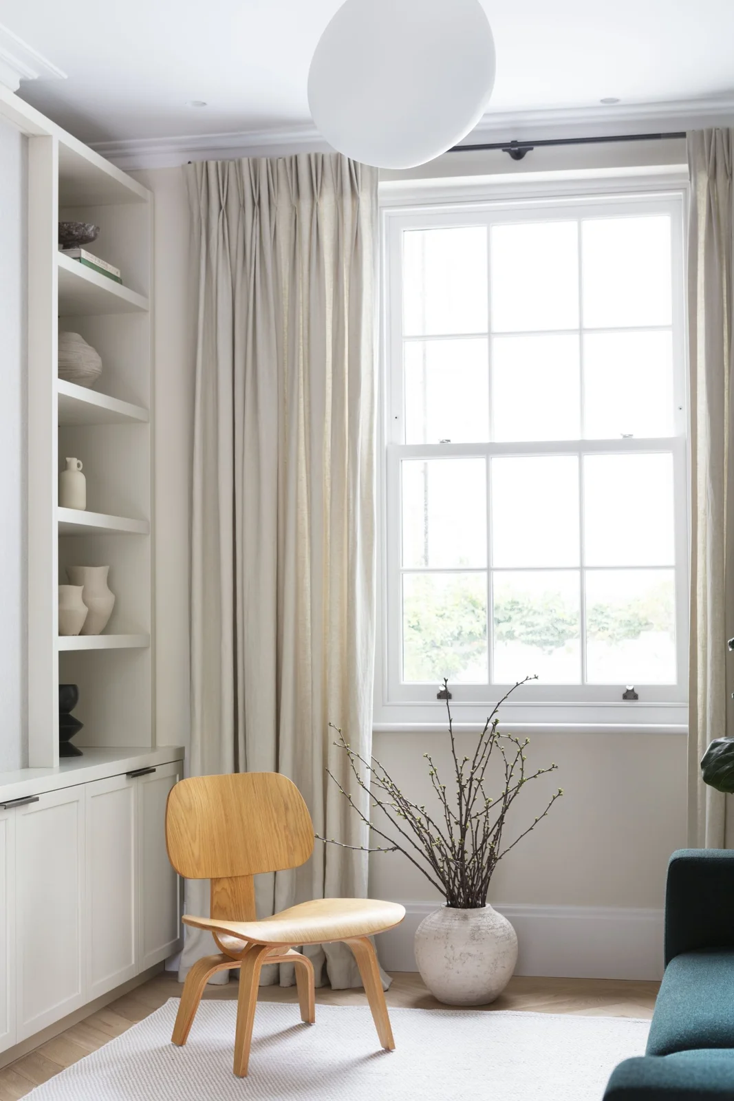 Timber chair beside a sash window and white display shelves