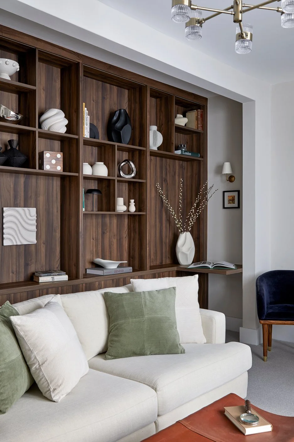Floor-to-ceiling shelving frames a sitting room with a pale sofa