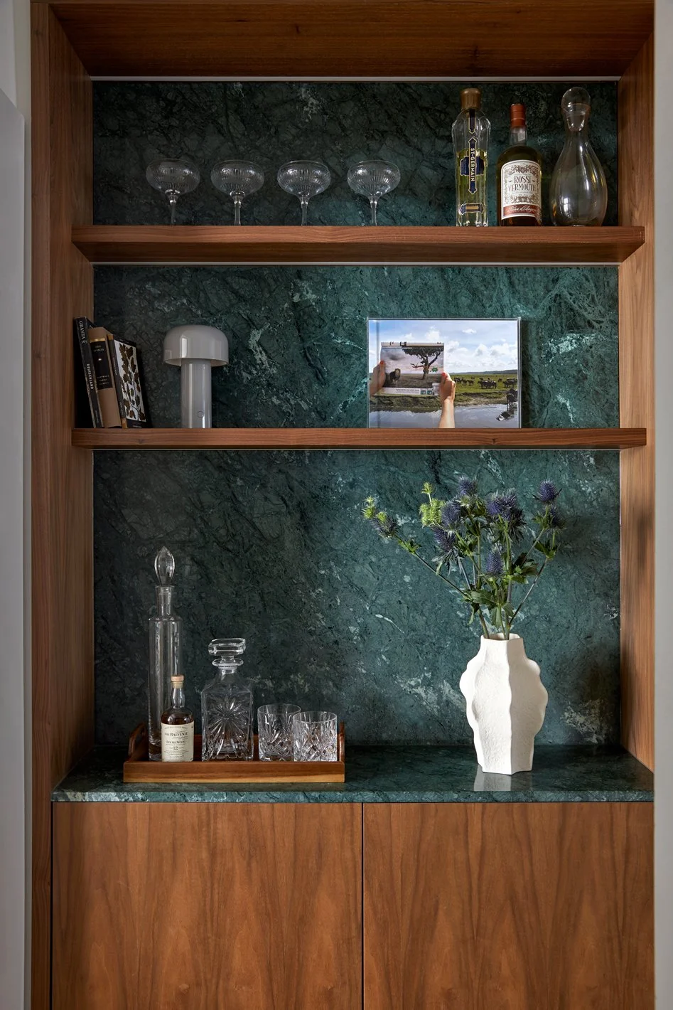 Glassware and small objects displayed against green patterned shelving